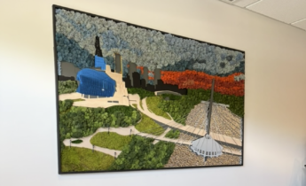 Framed textured wall art depicting a stylized Winnipeg cityscape, including the Canadian Museum for Human Rights, the Esplanade Riel bridge, greenery, autumn-colored trees, and a blue-and-white floral sky.