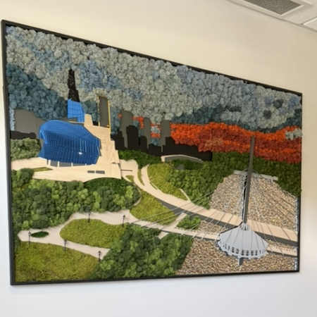 Framed textured wall art depicting a stylized Winnipeg cityscape, including the Canadian Museum for Human Rights, the Esplanade Riel bridge, greenery, autumn-colored trees, and a blue-and-white floral sky.